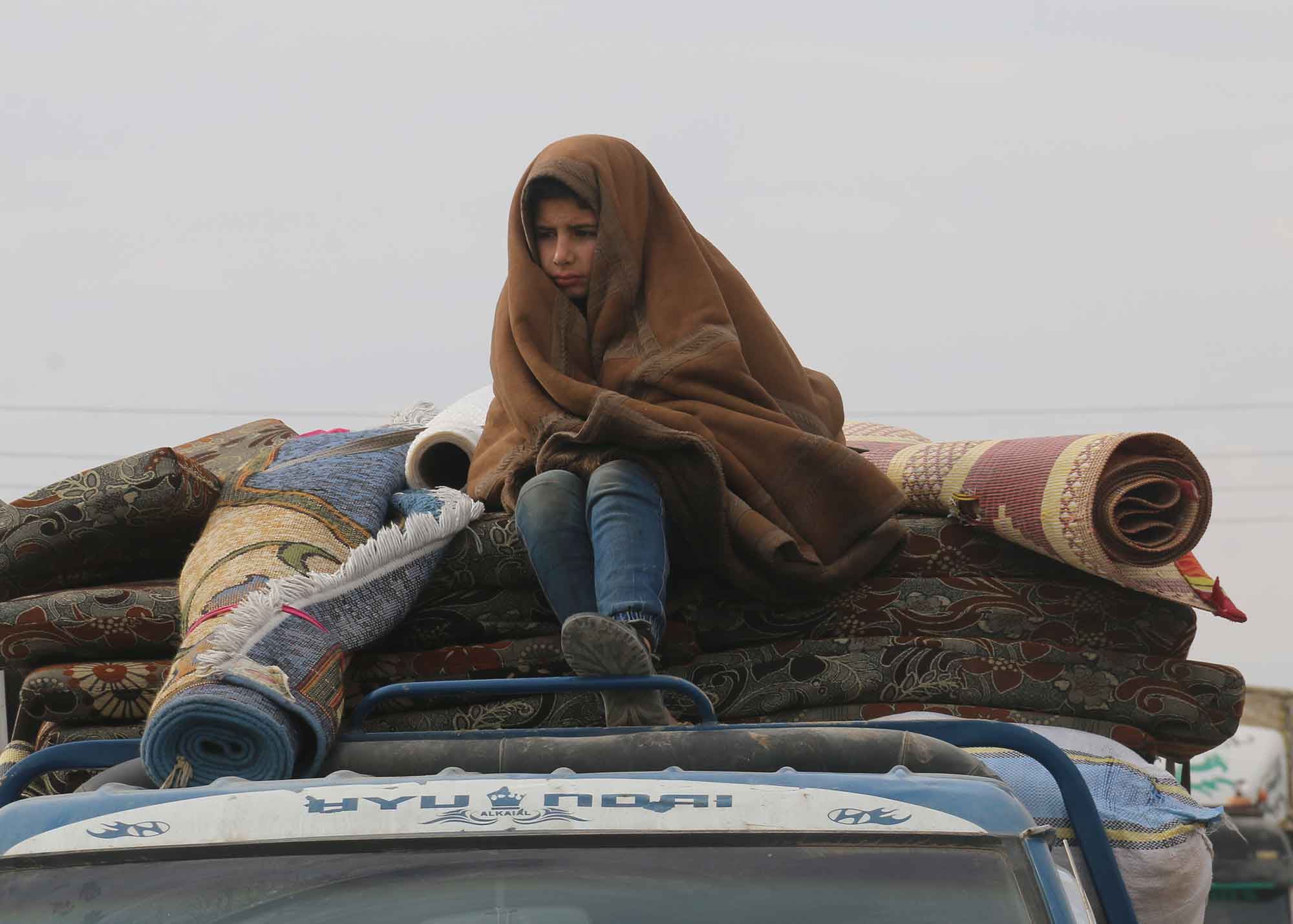 A Syrian refugee child in a rainy weather, a child sits on the roof of a car while fleeing the bombing of Idlib. Aleppo, Syria 17 April 2018 / Mohammad Bash